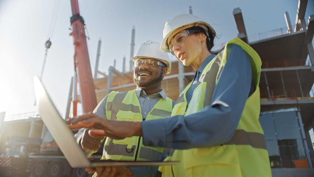 Two construction workers looking at a laptop